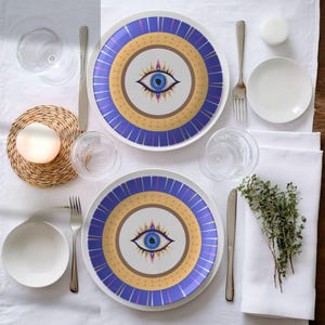 Dinner plate with evil eye design in blue, gold, and purple, placed on elegant table setting