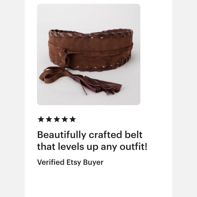May include: A wide brown suede belt featuring a wrap-around design with long tie ends that finish in fringe tassels. The edges of the belt are detailed with a decorative whipstitch pattern in a matching brown tone, creating a textured appearance.