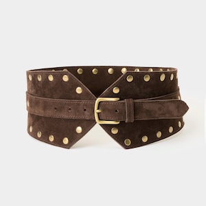 Può includere: Una cintura larga in pelle scamosciata marrone con fibbia dorata e borchie dorate. La cintura è progettata per essere indossata in vita.