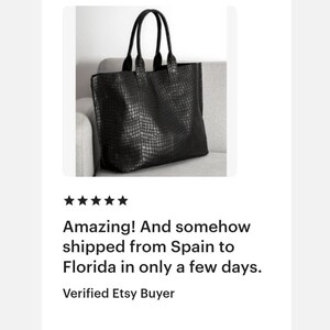 May include: A black tote bag featuring a textured crocodile skin pattern. The bag has two tall, sturdy handles attached to the top edge, a rectangular silhouette, and a spacious main compartment with a clean, structured design for daily use.