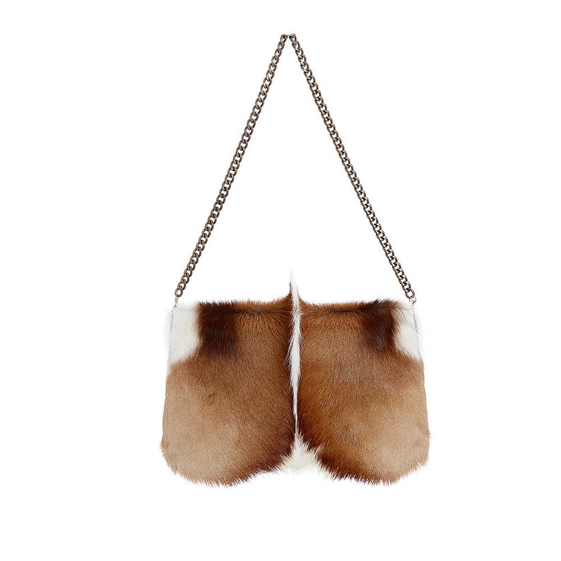 K&ouml;nnte beinhalten: Eine braune und wei&szlig;e Fellhandtasche mit einem silbernen Kettenriemen.