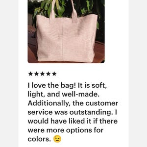 May include: A light pink tote bag featuring a textured, embossed crocodile skin pattern. The bag has two matching top handles and a rectangular silhouette with a vertical seam running down the center of the front panel.
