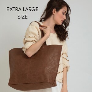 May include: An extra large brown tote bag with a textured crocodile skin pattern and two shoulder straps. The bag features a rectangular shape and a deep brown color. The text EXTRA LARGE SIZE is visible in the upper left corner of the image.