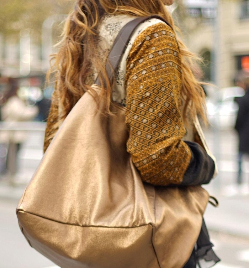 Extra large tote bag handmade in our atelier with soft metallic leather in bronze color. Reinforced leather handles for wearing it on the shoulder or by hand. A cool and lightweight tote with the magic touch of the metallic leather.