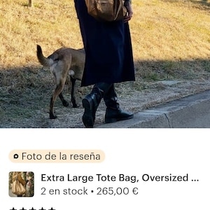 Puede incluir: Un bolso tote grande de cuero marr&oacute;n con una abertura ancha y un asa corta. El bolso lo lleva una persona que camina con un perro por un sendero.