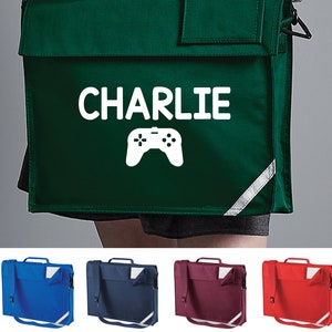 May include: A green school bag with a white reflective strip on the side. The bag has a white graphic of a video game controller and the name "CHARLIE" printed on the front.