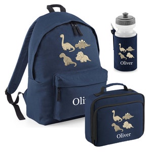May include: Navy blue backpack, lunch bag, and water bottle set. Each item features a beige dinosaur design and the name "Oliver" in white. The backpack has two zippered compartments and adjustable straps. The lunch bag has a handle.