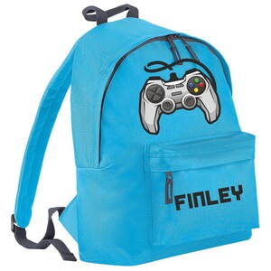 May include: A bright blue backpack with a black zipper and a grey video game controller graphic. The backpack has a front pocket with a black zipper and the name "FINLEY" printed in black.