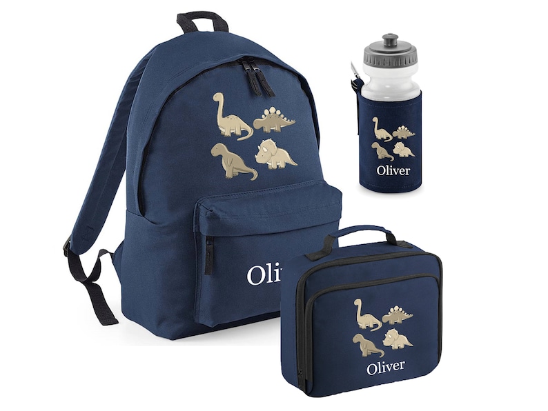 May include: Navy blue backpack, lunch bag, and water bottle set. Each item features a dinosaur design and the name "Oliver". The backpack has a front pocket and adjustable straps. The water bottle is in a navy blue holder.
