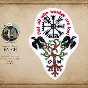 May include: A white fabric patch featuring black embroidery of a Vegvisir compass symbol, two black ravens, and a brown tree with green leaves. The text "not all who wander are lost" is embroidered in red thread in a circular arc above the compass.