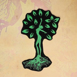 以下が含まれることがあります： 幹と根の中に人間のシルエットが入った木の緑色の刺繍パッチ。木は黒い背景になっています。