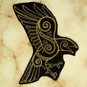 May include: Black felt patch with a gold embroidered design of a stylised raven with intricate details.