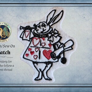 May include: An embroidered iron-on or sew-on patch featuring a white rabbit character wearing a dress decorated with red hearts. The rabbit has long ears, holds a scroll in one hand, and is outlined in black thread against a white fabric background.