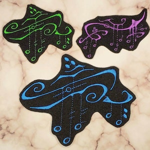 Könnte beinhalten: Drei gestickte Bügelbilder in Form von Musiknoten. Die Patches befinden sich auf einem hellbraunen Marmoruntergrund. Die Patches sind grün, blau und lila.