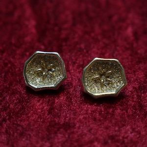 May include: A pair of gold-toned earrings with a star-shaped design set with clear rhinestones.