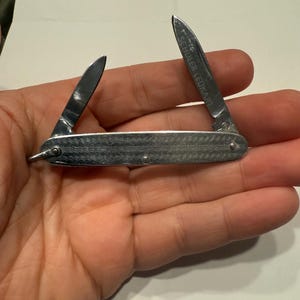 May include: A silver pocket knife with two blades, one of which is marked "SCHULLER LEUKART".