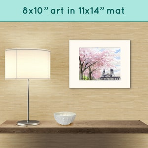 May include: A white matted print of a watercolor painting of a bridge with pink cherry blossoms. The print is 8x10 inches and is matted to 11x14 inches.