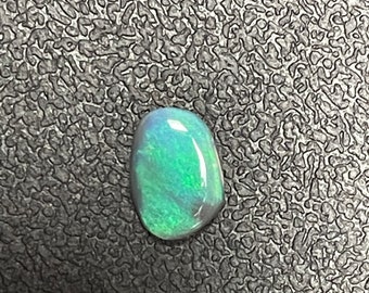 May include: A green and blue opal gemstone with a smooth, oval shape.