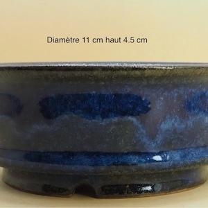 Peut inclure: Un pot à bonsaï en céramique bleue avec un bord foncé et un bord évasé. Le pot mesure 4,5 cm de haut et 11 cm de diamètre. Le pot a un glaçage bleu foncé avec des accents bleu clair.