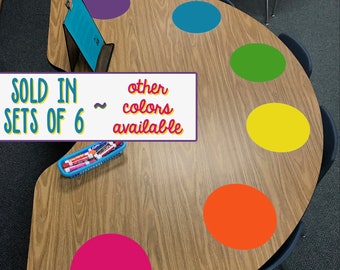 May include: A wooden table with a colorful paint palette design. The table is decorated with six large, colorful circles in purple, blue, green, yellow, orange, and pink. The text "SOLD IN SETS OF 6 ~ other colors available" is written on a white rectangle. The text "BOLD PACK" is written in green letters at the bottom of the table.