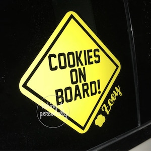 May include: Yellow warning sign with black text that reads "Cookies On Board!" with the name "Zooey" written below.