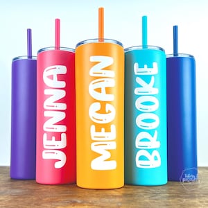 May include: Five colorful insulated tumblers with straws, each featuring a different name in white bubble letters: Jenna, Megan, and Brooke. The tumblers are in shades of purple, pink, orange, and blue. The straws match the tumbler colors.
