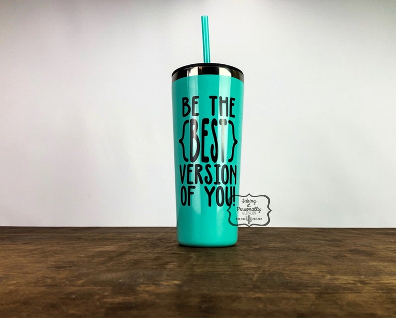 Puede incluir: Un vaso de acero inoxidable turquesa con tapa negra y pajita. El vaso tiene el texto "Be the {BEST} version of you!" impreso en &eacute;l.