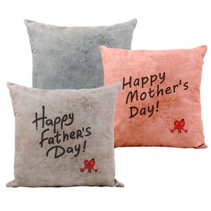May include: Three decorative throw pillows with a distressed, textured fabric. The pillows are beige, grey, and pink. The beige pillow has the text "Happy Father's Day!" and a red heart with legs. The pink pillow has the text "Happy Mother's Day!" and a red heart with legs.