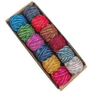May include: A cardboard box filled with twelve colorful yarn balls. The yarn balls are various colors, including blue, green, red, brown, purple, gold, and pink. The yarn is tightly wound and appears to have a metallic sheen.