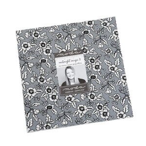 May include: A square fabric piece with a floral pattern in white and black on a gray background. The fabric has a tag that reads "Midnight Magic 2" and features a woman's image. The fabric is from Moda Fabrics + Supplies.