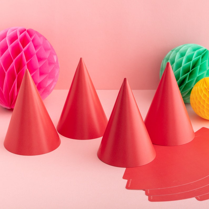 May include: Four red party hats with a honeycomb ball and a green honeycomb ball in the background.