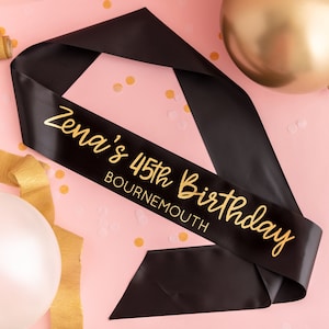 May include: Black satin sash with gold lettering that reads "Zena's 45th Birthday Bournemouth".