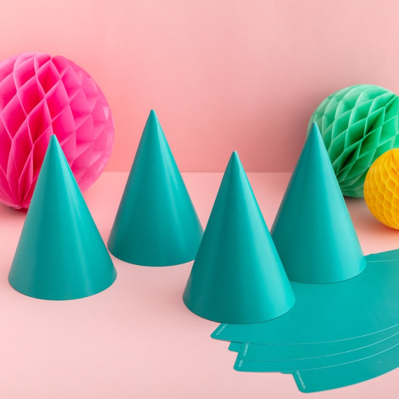 May include: Four teal blue party hats with a pink honeycomb ball and a green honeycomb ball in the background. The party hats are made of paper and have a pointed tip. The honeycomb balls are decorative and are made of paper.