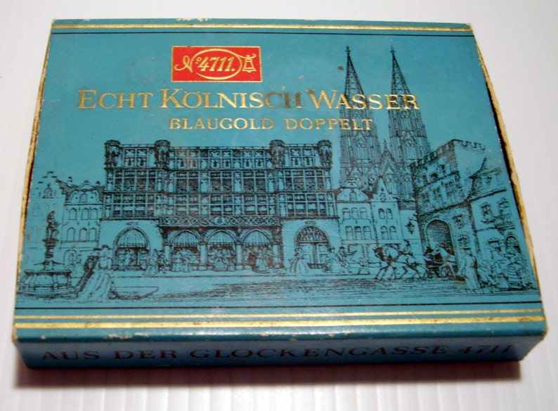 Puede incluir: Una caja azul con ribetes dorados y una ilustraci&oacute;n en blanco y negro de un horizonte urbano. La caja tiene el texto "No. 4711. Echt Kolnisch Wasser Blaugold Doppel" y "Aus der Glockengasse 4711" impreso en ella.
