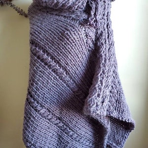 May include: A gray knitted shawl with a button closure. The shawl is made of a soft, textured yarn and has a loose, drapey fit.