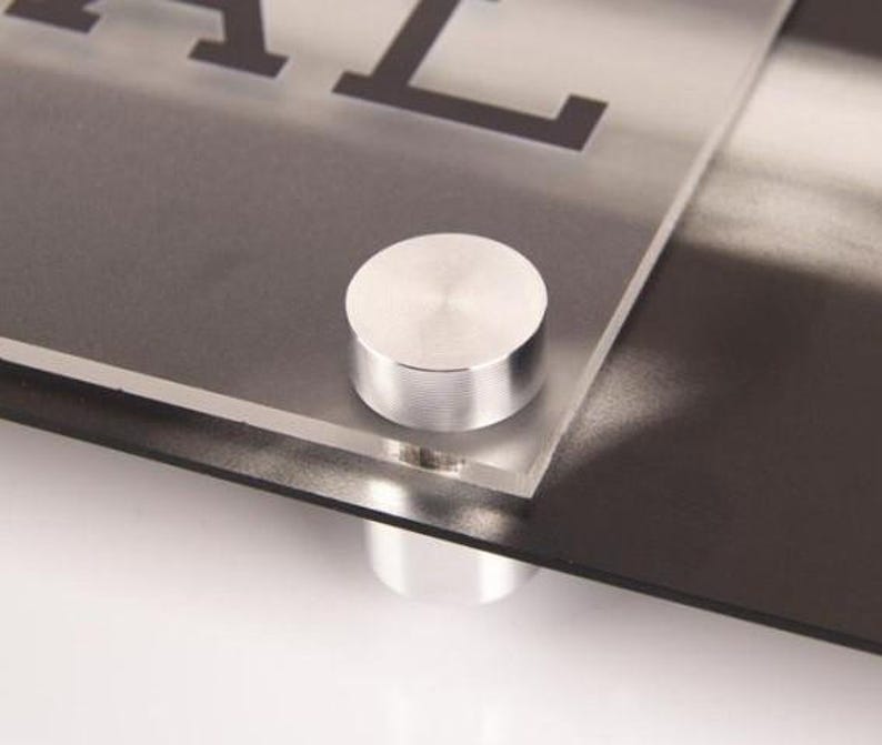 Peut inclure: Une tasse en c&eacute;ramique blanche avec une anse noire et le texte "But First, Coffee" en noir, dans une police manuscrite. La tasse est pos&eacute;e sur une surface blanche.