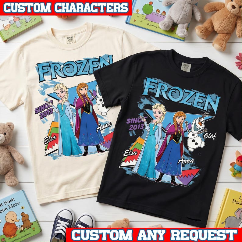 May include: Two short-sleeve t-shirts, one cream and one black, featuring a graphic print of Frozen characters Elsa, Anna, and Olaf. The design includes the text Frozen, Since 2013, Elsa, Anna, and Olaf, with colorful geometric shapes in the background.