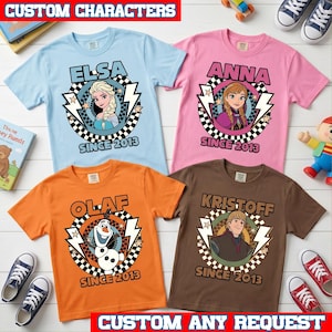 May include: Four short-sleeve t-shirts in light blue, pink, orange, and brown. Each features a circular graphic with a character from Frozen, lightning bolts, a checkered border, and the text "SINCE 2013" below the character's name.