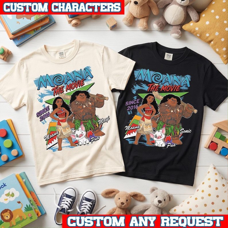 May include: Two short-sleeve t-shirts, one cream and one black, featuring a graphic print of Moana, Maui, and Pua. The design includes the text Moana The Movie, Since 2016, and character names. The shirts have a crew neckline and a standard fit.