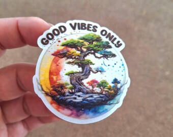 May include: A white sticker with a colorful illustration of a tree with the text "GOOD VIBES ONLY" in a brown circle.