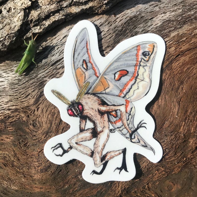 May include: A white sticker with a detailed illustration of a moth with a human-like body. The moth has large wings with orange, white, and gray markings. The moth's body is brown and furry, with red eyes.
