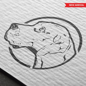 May include: A black ink line drawing of a dog head in profile, enclosed within a circular border. The dog has a prominent snout and visible eye detail. A red banner in the top right corner contains the white text NEW ARRIVAL.