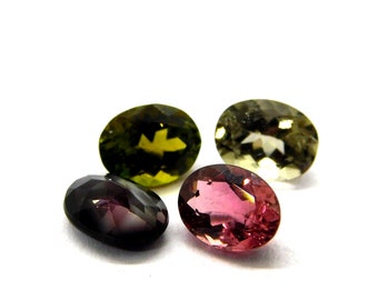 May include: Four oval-shaped gemstones in various colors: green, yellow, pink, and purple. The gemstones are faceted and have a glossy finish.