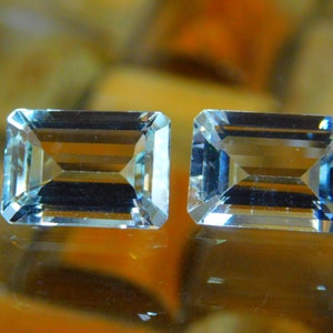 May include: Two light blue aquamarine gemstones cut in an emerald shape.