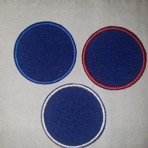 May include: Three round blue fabric patches with different colored borders. The left patch has a blue border, the middle patch has a red border, and the right patch has a white border.