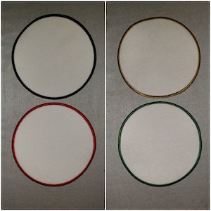 May include: Four blank, white, round patches with different colored borders. The top left patch has a black border, the top right patch has a gold border, the bottom left patch has a red border, and the bottom right patch has a green border.