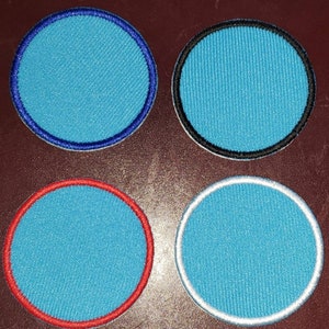 May include: Four circular patches with a light blue center and different colored borders. The borders are blue, black, red, and white. The patches have a textured appearance.