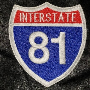 May include: A blue and red interstate highway sign with white text and the number 81.