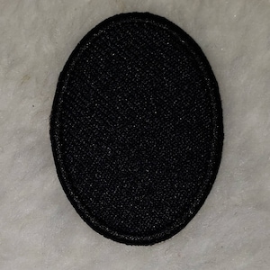 May include: A black oval-shaped fabric patch with a stitched edge.