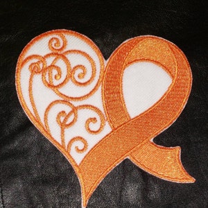 May include: Orange ribbon in the shape of a heart with a white embroidered design. The ribbon is a symbol of support for various causes.